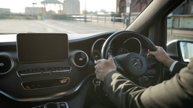 Close-up of a Mercedes dashboard and streering wheel driven by a chauffeur